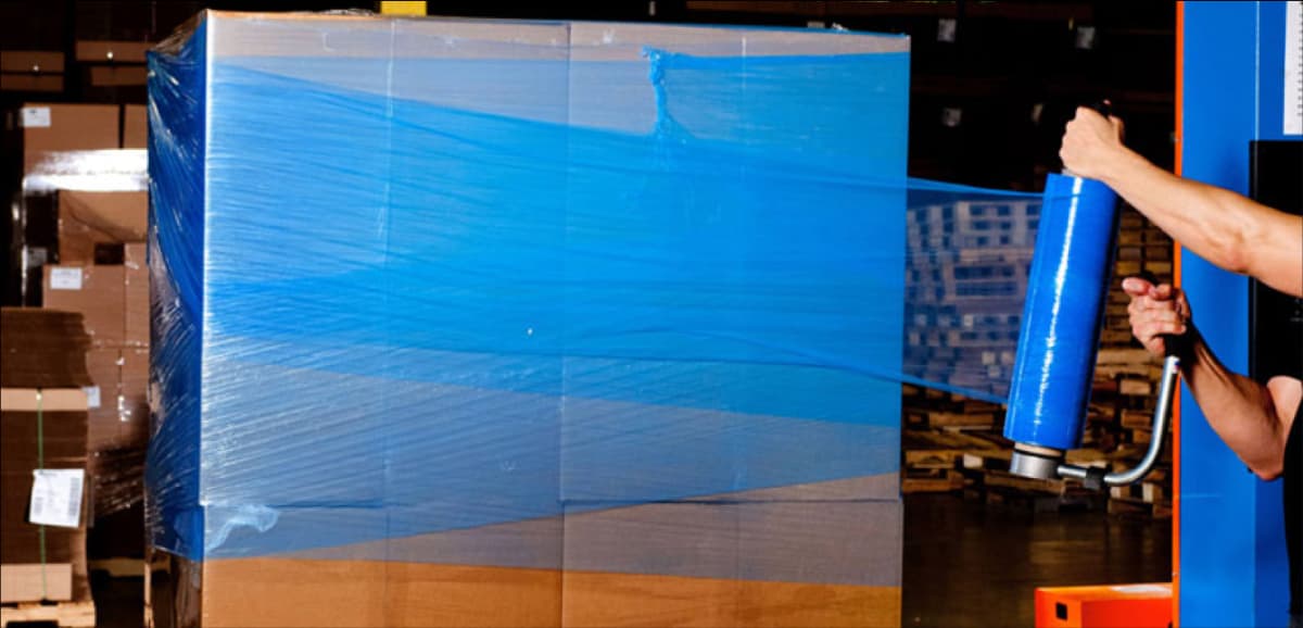 Ingenieros organizando mercancia con pelicula estirable