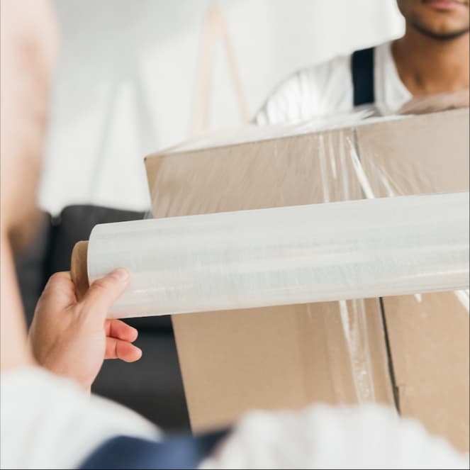 Protegiendo Mercancias con pelicula estirable de color en almacen de empresa de logistica